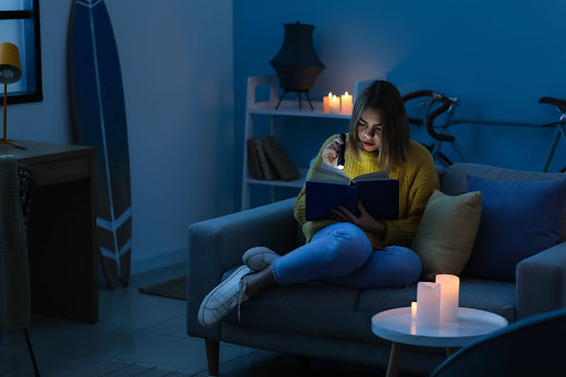 Woman sitting in her living room surrounded by candles during a blackout.